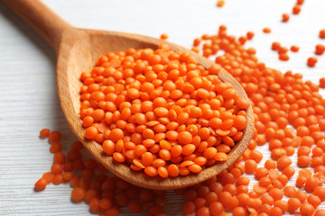 Red spoon of lentils on wooden background