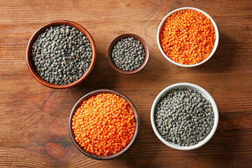 Bowls with red and black lentils on wooden background