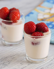 yogurt with strawberries in a glass on wooden table with blue napkin