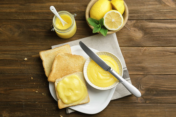 Composition with fresh toasts and delicious lemon curd on wooden table