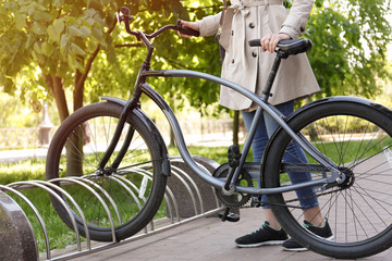 Young woman parking bicycle outdoors