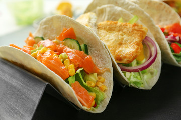 Stand with tasty fish tacos on dark table