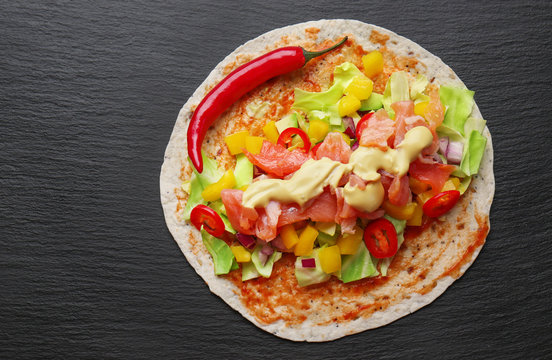 Fish taco with salmon and chili pepper on dark background