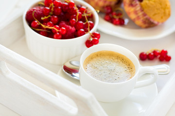 Traditional breakfast: espresso, fruit muffins and ripe berries on white wooden salver. Selective focus