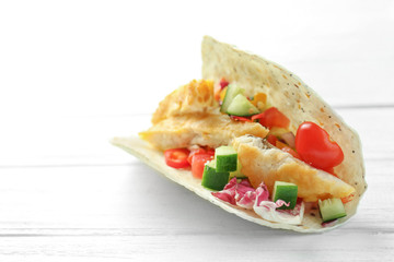 Tasty fish taco on white wooden background