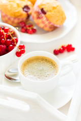 Traditional breakfast: espresso, fruit muffins and ripe berries on white wooden salver. Selective focus