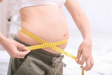 Pregnant woman measuring her belly at home. Pregnancy weight gain concept