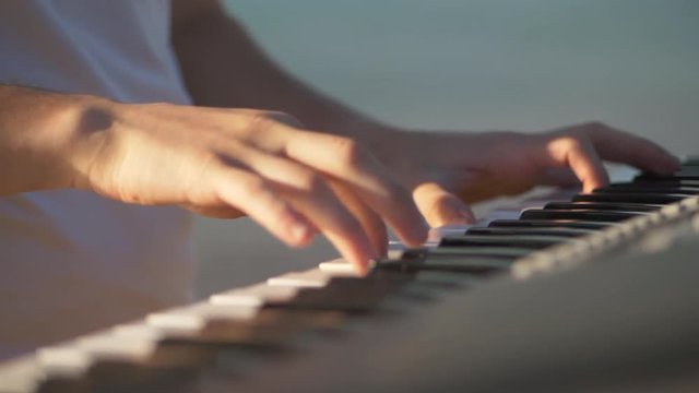 hands of men play on the synth. Man hands playing a MIDI controller keyboard synthesizer. Close up slowmotion video full hd.