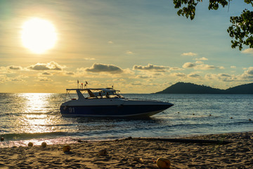 Boat on the island beach, scenic sunset seascape with clouds on the sky