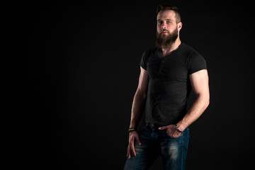 A charismatic and stylish man with a beard stands full-length on a black isolated background. Horizontal frame