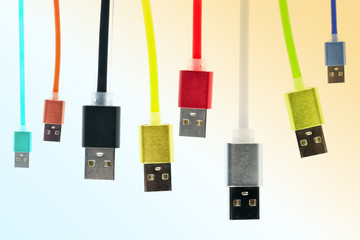 Eight multicolored usb cables hang vertically, on a gradient, tinted isolated background. The family unites. future technologies. Horizontal frame