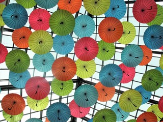 Multi colored umbrellas hanging from a ceiling in a mall