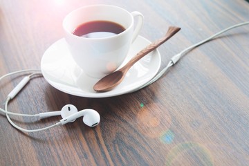 Earphones and coffee cup on wooden table, Lifestyle concept