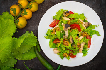 Fresh salad with chicken, mushrooms, lettuce, tomato and mustard dip. Dark stone background. Top view. Close-up