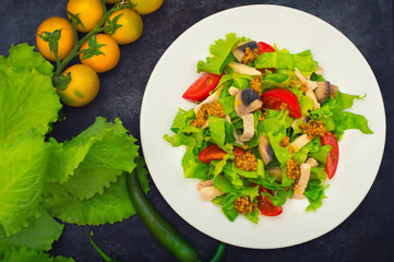 Fresh salad with chicken, mushrooms, lettuce, tomato and mustard dip. Dark stone background. Top view. Close-up