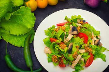 Fresh salad with chicken, mushrooms, lettuce, tomato and mustard dip. Dark stone background. Top view. Close-up