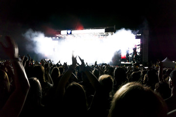 Fototapeta na wymiar silhouettes of concert crowd in front of bright stage lights. Dark background, smoke, concert spotlights