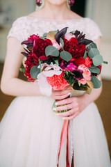 the bride holds a bouquet with white, red, yellow, purple and white flowers
