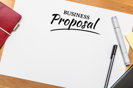 Top view of business proposal on table with book, pen, post-it note