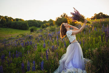 Stunning lady in white dress stands with bouquet on the field