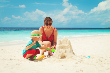 mother and son building castle on beach