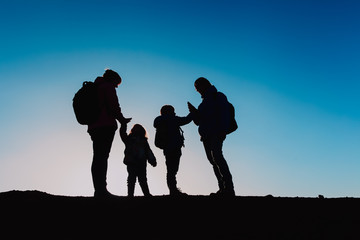 Silhouettes of family with two kids hiking at sunset