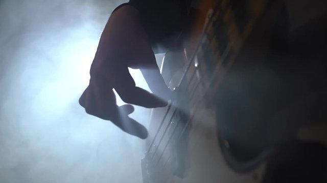 Man playing bass guitar at a rock concert. closeup