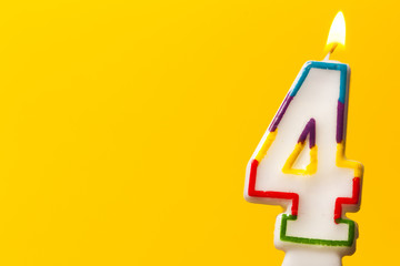 Number 4 birthday celebration candle against a bright yellow background