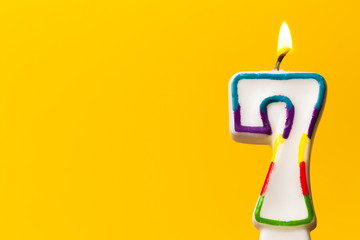 Number 7 birthday celebration candle against a bright yellow background