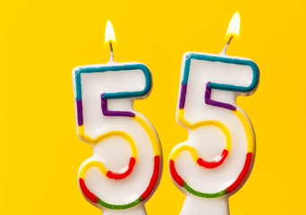 Number 55 birthday celebration candle against a bright yellow background