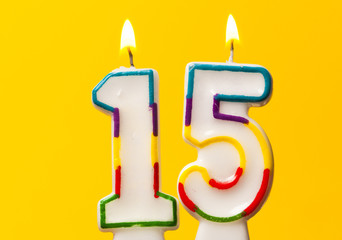 Number 15 birthday celebration candle against a bright yellow background