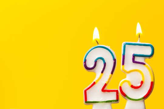 Number 25 birthday celebration candle against a bright yellow background