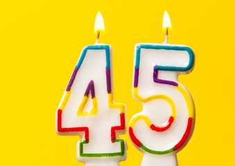 Number 45 birthday celebration candle against a bright yellow background
