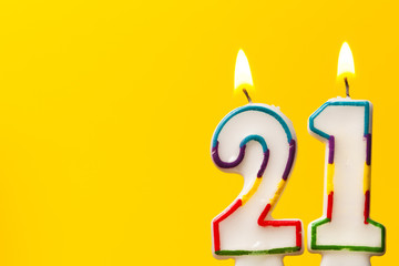 Number 21 birthday celebration candle against a bright yellow background - obrazy, fototapety, plakaty
