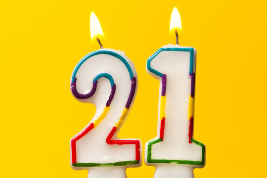 Number 21 birthday celebration candle against a bright yellow background