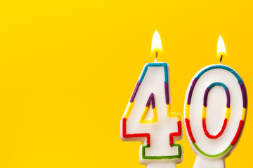 Number 40 birthday celebration candle against a bright yellow background