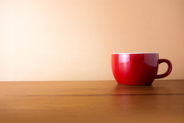 red hot coffee cup with wood desk in warm tone color