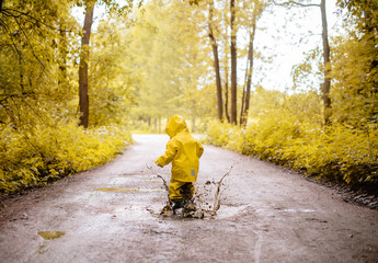 Little girl jumping fun in a dirty puddle