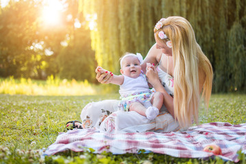 Young mother having fun with her baby daughter in the park at sunset.