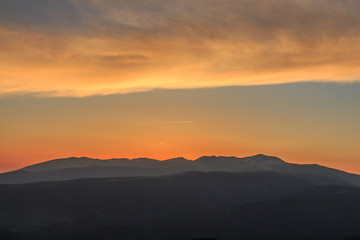 Fototapeta na wymiar Orange sunrise with mountains. Atmospheric phenomena concept