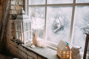 Candles, white latern, owl with decor on the windowsill