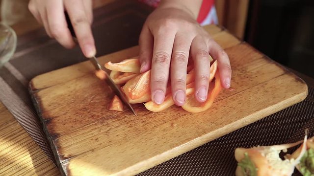 A girl cuts a Bulgarian pepper on a cutting board in the kitchen,