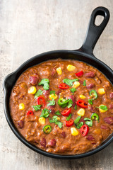 Traditional mexican tex mex chili con carne in a frying pan on wooden table
