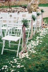 decorated outdoor wedding ceremony white wooden chairs and flowers