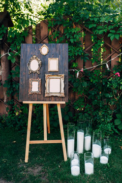 frames for gests list on wooden background, white candles on a grass