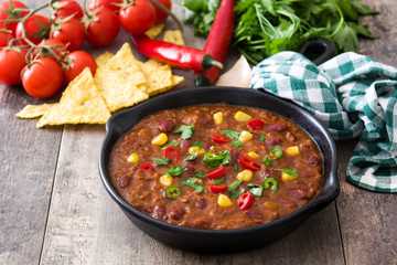 Traditional mexican tex mex chili con carne in a frying pan on wooden table
