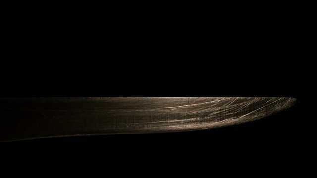Light moves on a blade of a knife macro on a black background