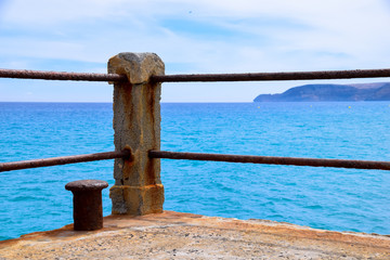 Fototapeta premium Concrete post of rusty ship bollard at the end of a concrete pier overlooking the Atlantic Ocean