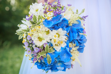 Beautiful wedding bouquet on a background of white dresses