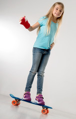 junges Mädchen fährt auf Skateboard mit Gipsarm und lächelt in die Kamera